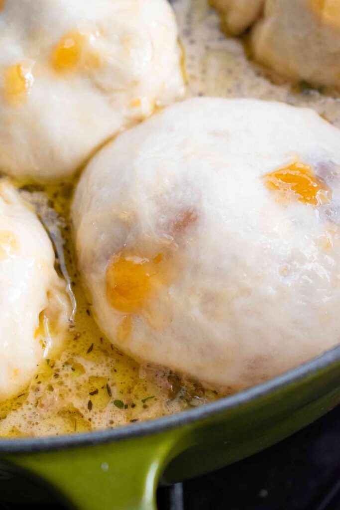Dumpling scoops on top of the cooked creamy chicken stew