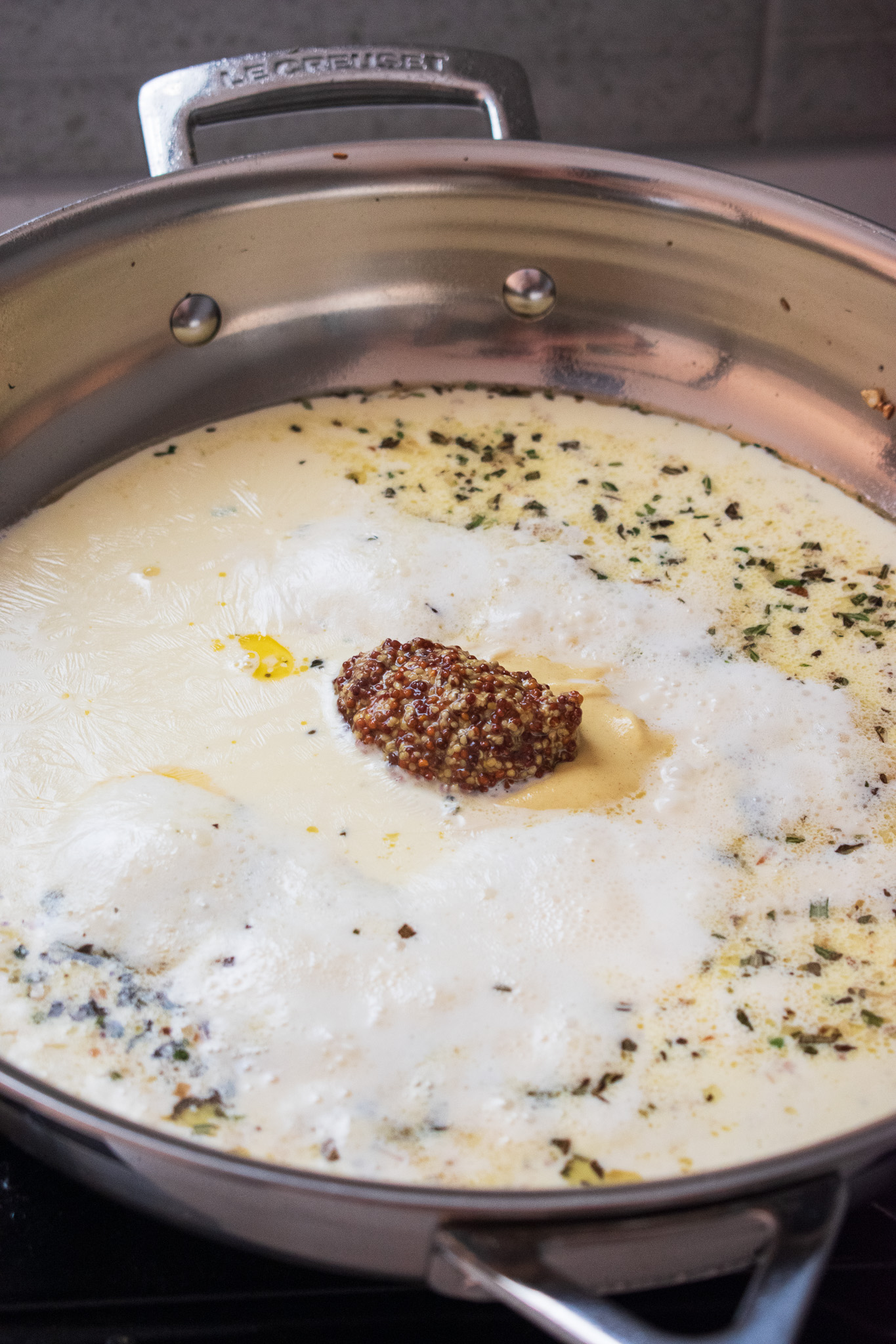 Mustard sauce in a stainless steel pan on the top of a stove. #dijonmustard #pork 