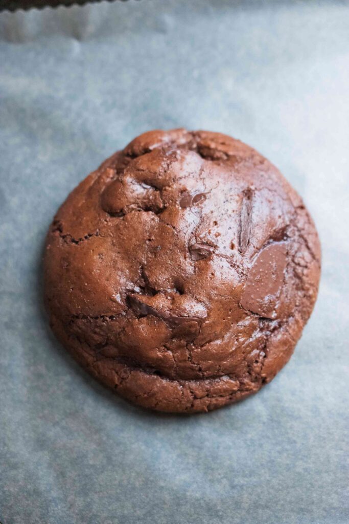 A chocolate brownie cookies on a baking tray. One single chocolate brownie cookie.